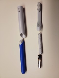 Quip electric toothbrush parts and accessories: handle, toothbrush head, motor, a AAA battery, and a plastic cover for the top half of the toothbrush